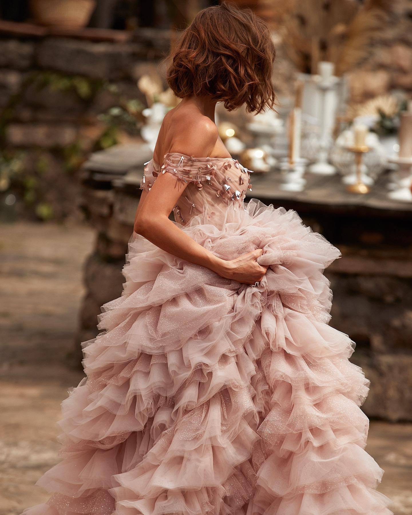 Vestido de novia rosa de una línea con hombros descubiertos y falda de pastel con pedrería y tachuelas de princesa